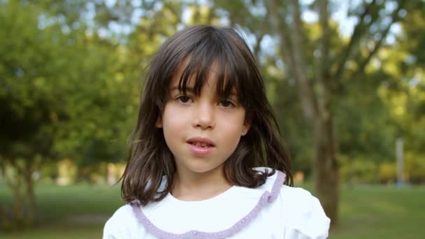 Pensive schattig klein zwart harig meisje staan in de stad park — Stockvideo