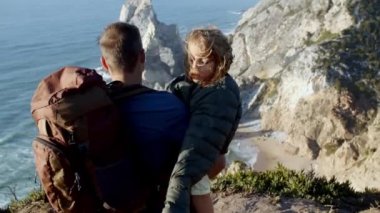 Sırt çantalı baba kızını kucağında tutuyor.