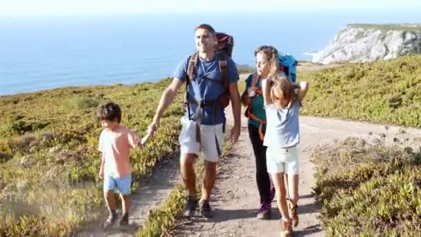 Aktív szülők hátizsákkal és a tengeren sétáló gyerekekkel — Stock videók