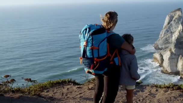 Mor med camping rygsække og datter barn stående ved klippen – Stock-video