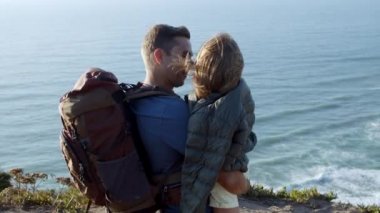 Baba sırt çantasıyla kucağında bir kız çocuğu taşıyor.