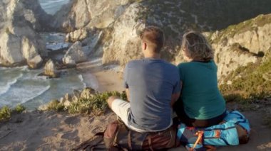 Bir çift turist mola veriyor, uçurumda oturuyor.