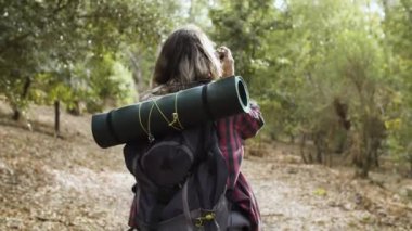 Ormanın fotoğraflarını çeken kameralı genç bir gezgin kız.