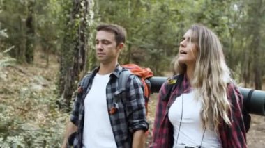 Sırt çantalı bir çift gezgin orman yolunda yürüyor.