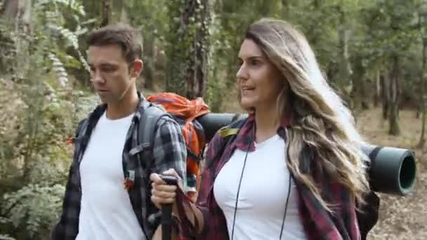Casal de turistas falando enquanto carrega mochilas de acampamento — Vídeo de Stock