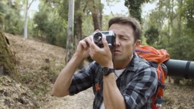 Fotoğraf makineli sırt çantalı adam ormanın fotoğraflarını çekiyor.