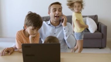 Umursayan baba akıllı telefonda konuşuyor, masada oturuyor.