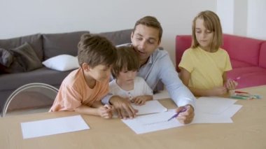 Gülümseyen baba çocuklarla konuşuyor ve keçeli kalemle çiziyor.
