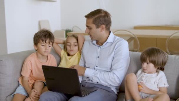 Daddy and three sibling kids relaxing on couch at home — Stock Video