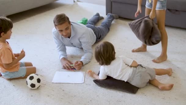 Enfants frères et sœurs et papa couchés sur le sol chaud avec des coussins — Video