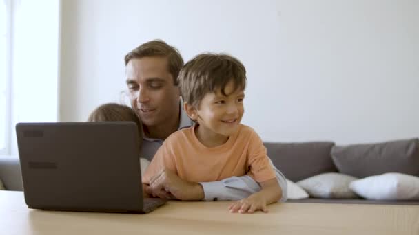 Ojciec pokazuje coś małym synom na laptopie. — Wideo stockowe