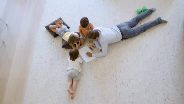 Vue du dessus des frères et sœurs enfants et papa assis et couché sur le sol — Video