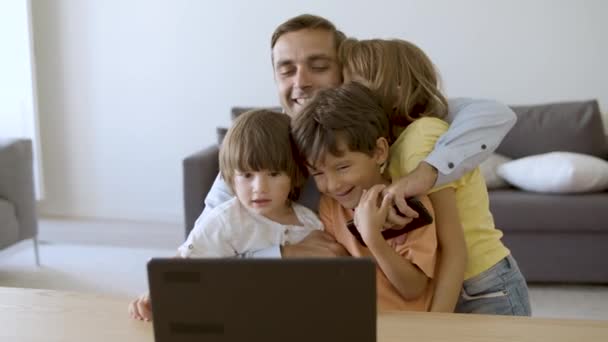 Liebender Vater umarmt Kinder und blickt auf Laptop-Bildschirm — Stockvideo