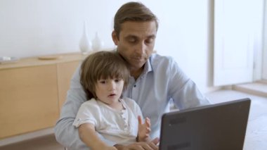 Babası kucağında küçük bir çocuk tutuyor.