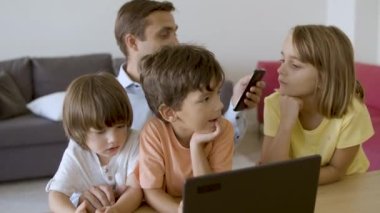 Babam tatlı çocuklarla oturuyor ve akıllı telefon kullanıyor.