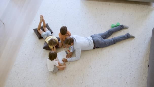 Vue du dessus des enfants frères et sœurs et papa assis et couché sur le sol chaud — Video