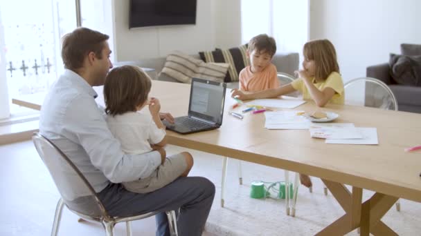 Babam dizüstü bilgisayarla çalışırken mutlu çocuklar karalama yapıyor. — Stok video