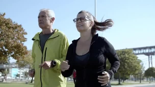 Paar reifer Läufer joggt die Straße hinunter — Stockvideo