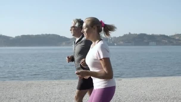 Active couple training, jogging along sea and smiling — Stock Video