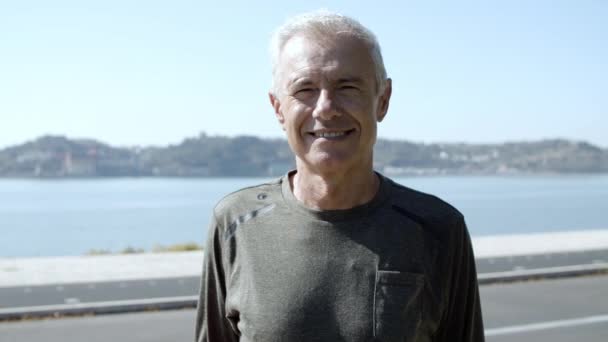 Hombre de 60 años activo positivo en ropa deportiva de pie al aire libre — Vídeos de Stock