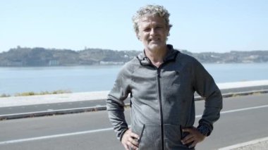 Mutlu aktif olgun 60 'lı yaşlarda erkek spor kıyafetleri içinde dışarıda dikiliyor.