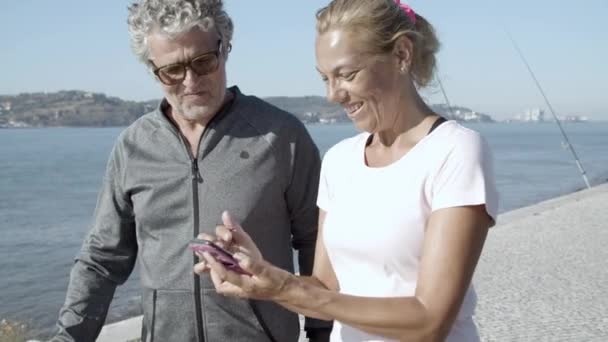 Happy people in sportswear walking and watching phone screen — Stock Video