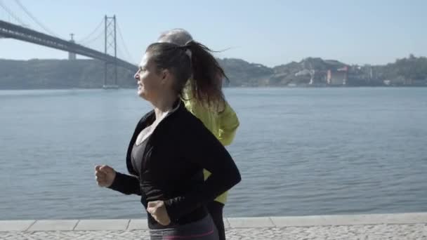 Sporty runners exercising together near lake in sunny day — Stock Video