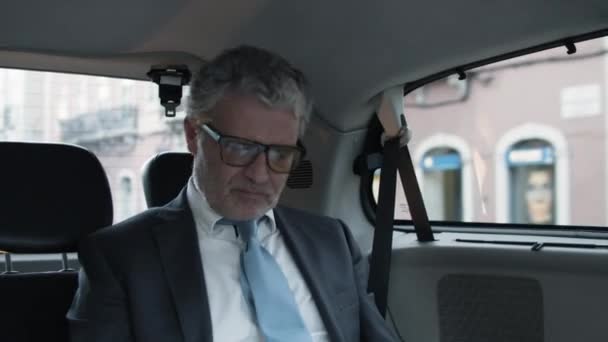 Starší vousatý podnikatel sedící na zadním sedadle jedoucího auta — Stock video