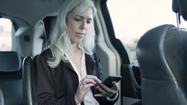 Serious businesswoman driving in car and texting message. — Stock Video