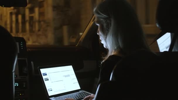 Zakenvrouw met laptop tijdens het rijden in de auto 's nachts. — Stockvideo