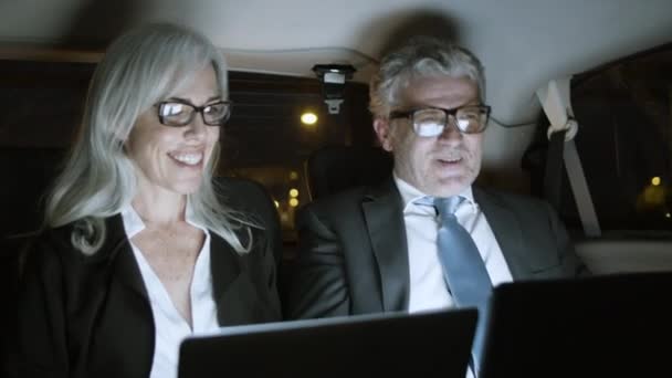 Zakelijke partners met behulp van laptop tijdens het rijden in de auto 's nachts. — Stockvideo