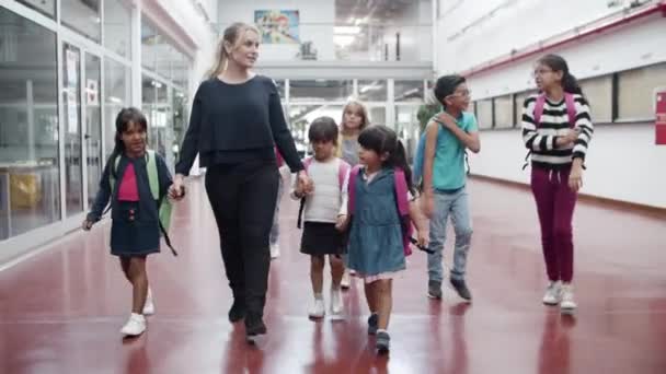 Enfants de différents âges marchant dans le couloir avec tuteur. — Video