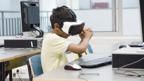 Boy sitting in front of monitor, wearing VR glasses. — Stock Video