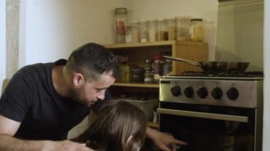 Neşeli baba ve kız mutfakta fırın bakıyorlar..