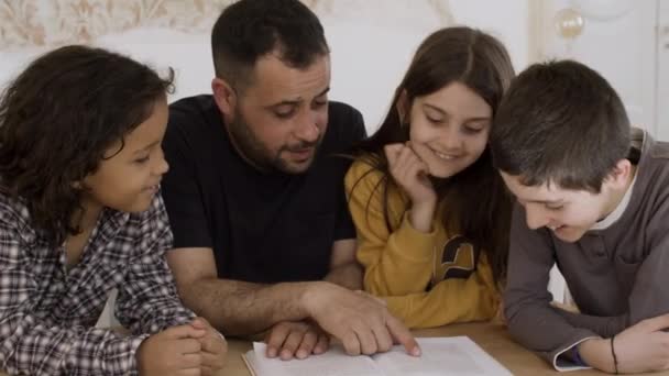 Pai paciente estudando com crianças alegres em casa. — Vídeo de Stock