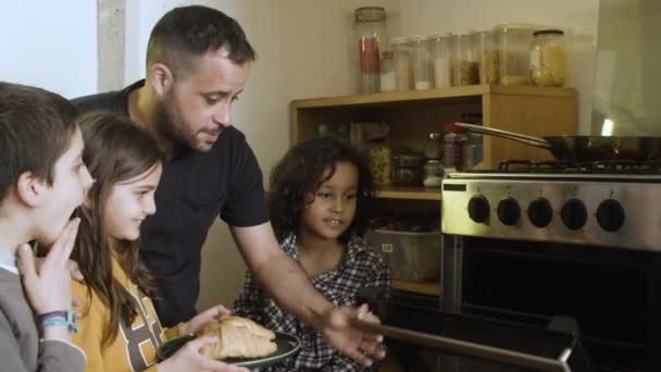 Konzentrierter Papa heizt mit Kindern Essen im Ofen vor. — Stockvideo