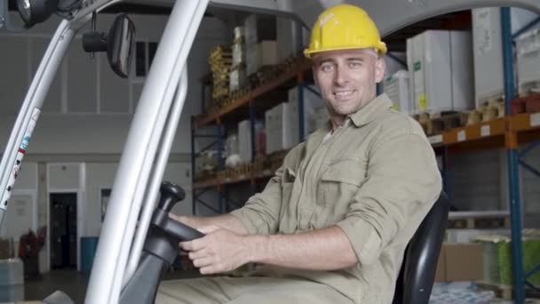 Cheerful male factory worker sitting in forklift in warehouse. — Αρχείο Βίντεο