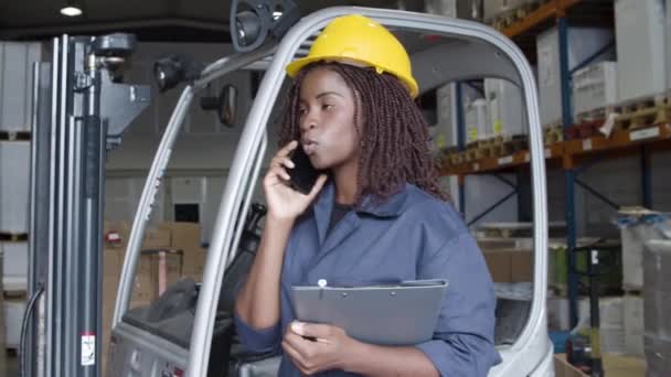 Excited female factory employee in helmet talking on phone. — Stock Video