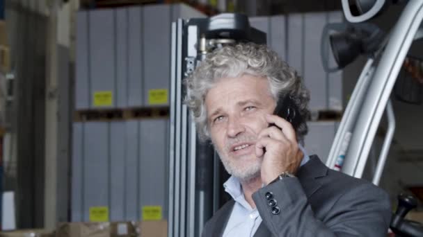 Vrolijke zakenman die in het magazijn staat te telefoneren. — Stockvideo
