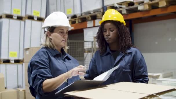 Összpontosított, sokszínű női munkás beszél a raktárban. — Stock videók