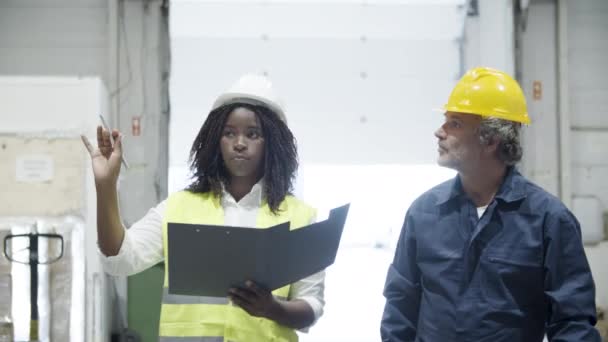 Fokuserede arbejdere går gennem lagerbygning og taler. – Stock-video