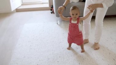 Mutlu küçük kız oturma odasında ilk adımlarını atıyor..