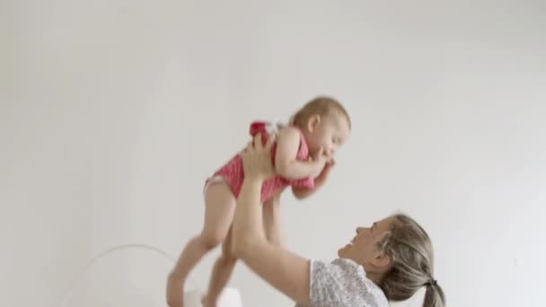 Uśmiechnięta mama wychowująca swoją córeczkę i całująca się. — Wideo stockowe