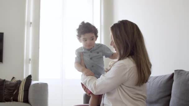 Mãe excitada sentada no sofá, segurando o filho nas mãos. — Vídeo de Stock