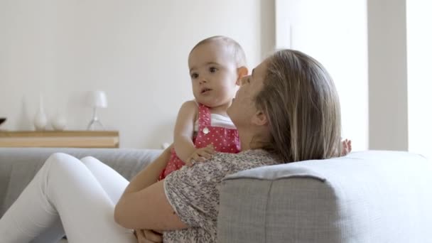 Anya a kanapén fekszik és a kislányát a kezében tartja.. — Stock videók