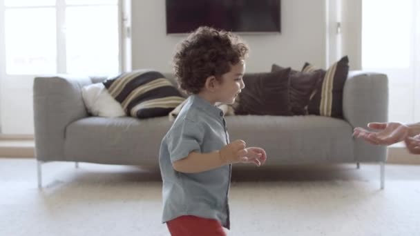 Criança alegre em pé na sala de estar, apontando para cima. — Vídeo de Stock