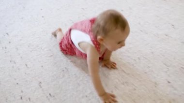 Güzel çocuk oturma odasında halıda sürünüyor..