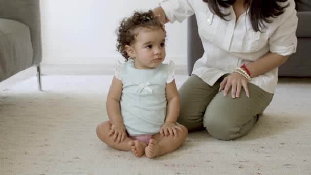 Serious girl sitting on carpet with mom at home. — Stock Video