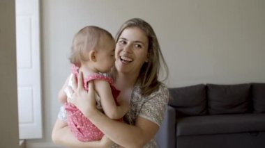 Neşeli bekar anne oturuyor ve bebeğini kucağında tutuyor..