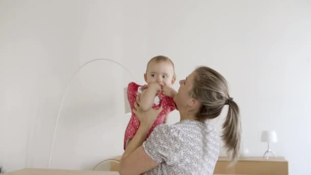Mãe feliz levantando bebê acima da cabeça e beijando-a. — Vídeo de Stock
